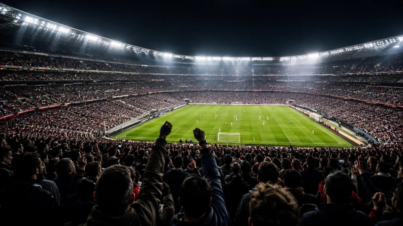 Vyprodaný fotbalový stadion plný fanoušků s šálami za večerního zápasu pod reflektory - zájezdy za fotbalem 2026 - fman.cz